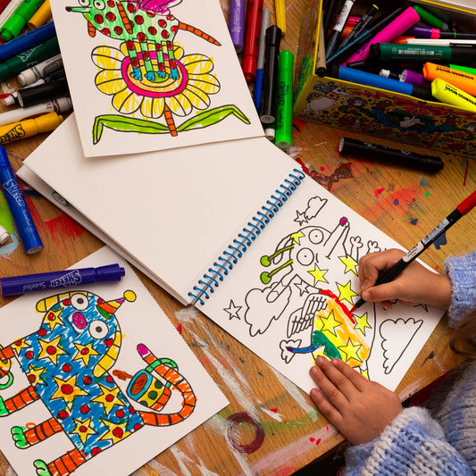 Coloring books and markers on a table with a child coloring.