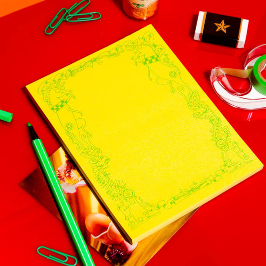 Bright yellow notepad with a green border of delightfully unhinged drawings of dogs and unicorns