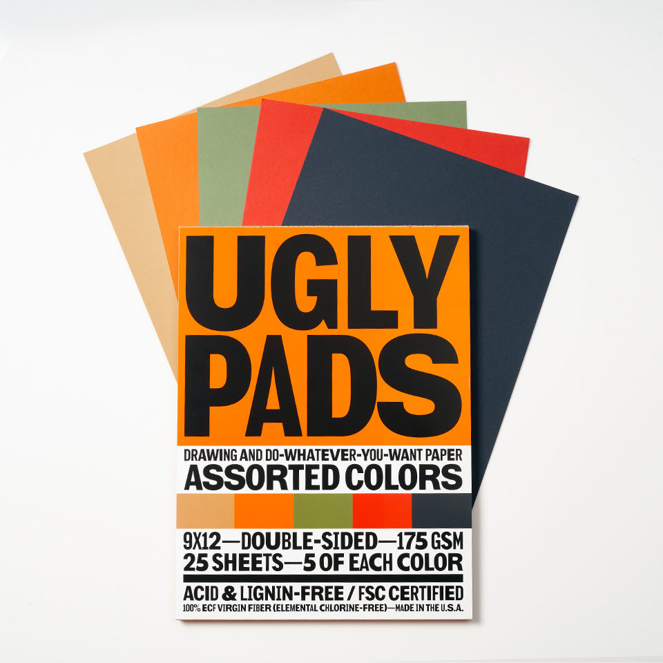 Packaging of "farmer" uglypad with single sheets spread around it in kraft, orange, sage, coral, and navy