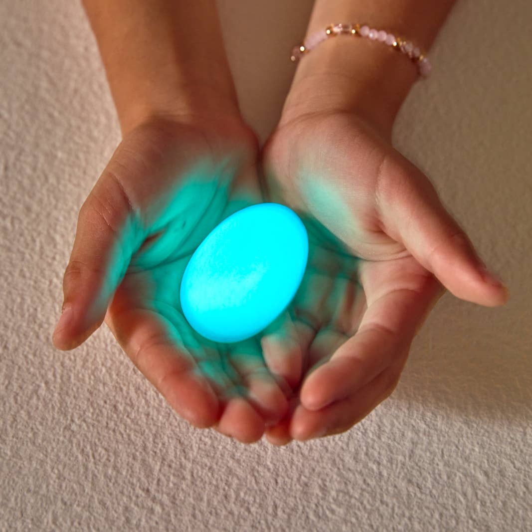 blue glow stone being held by two white hands