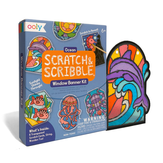 Ooly Scratch & Scribble Ocean Window Banner Kit shown with its retail box and a completed stained-glass-style ocean banner featuring a purple dolphin, orange fish, and blue waves on a white background.