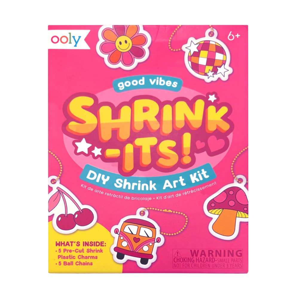 Front of a pink Ooly DIY Shrink Art Kit box, featuring colorful cartoon graphics including a flower, disco ball, cherries, mushroom, van, and the title 'SHRINK -ITS!'.