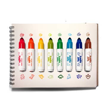 A spiral-bound notebook or sketchpad showing eight colorful jumbo markers, each with a different color doodle and showing the different types of dinos in red, orange, yellow, olive, green, teal, blue, and brown