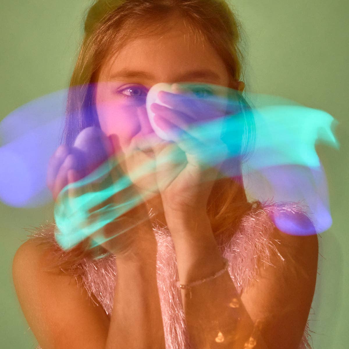a white child with long brown hair waves a glow stone in front of her face