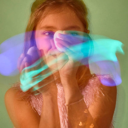 a white child with long brown hair waves a glow stone in front of her face