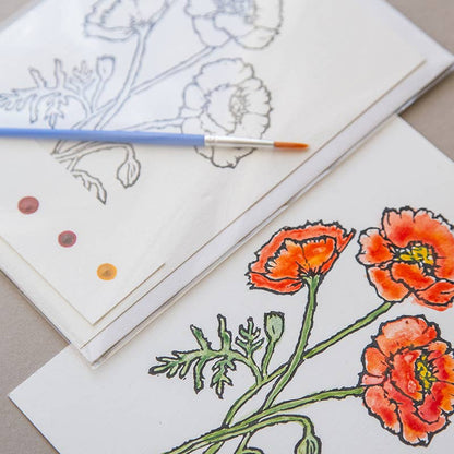 Card with an illustration of poppies with watercolors and a paintbrush on a grey background