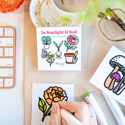 a hand in the process of coloring in a page featuring an pastel orange dahlia and pink and brown mushrooms