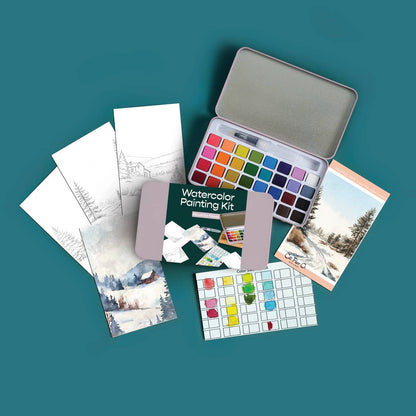 Midwinter Forest watercolor painting kit arranged on a teal background, including a metal tin of watercolor paints, a green watercolor paper pack, sample painting cards, and sketch papers.