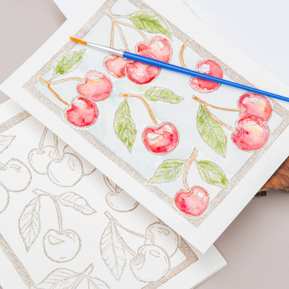 Card with an illustration of cherries with a paintbrush on a white surface