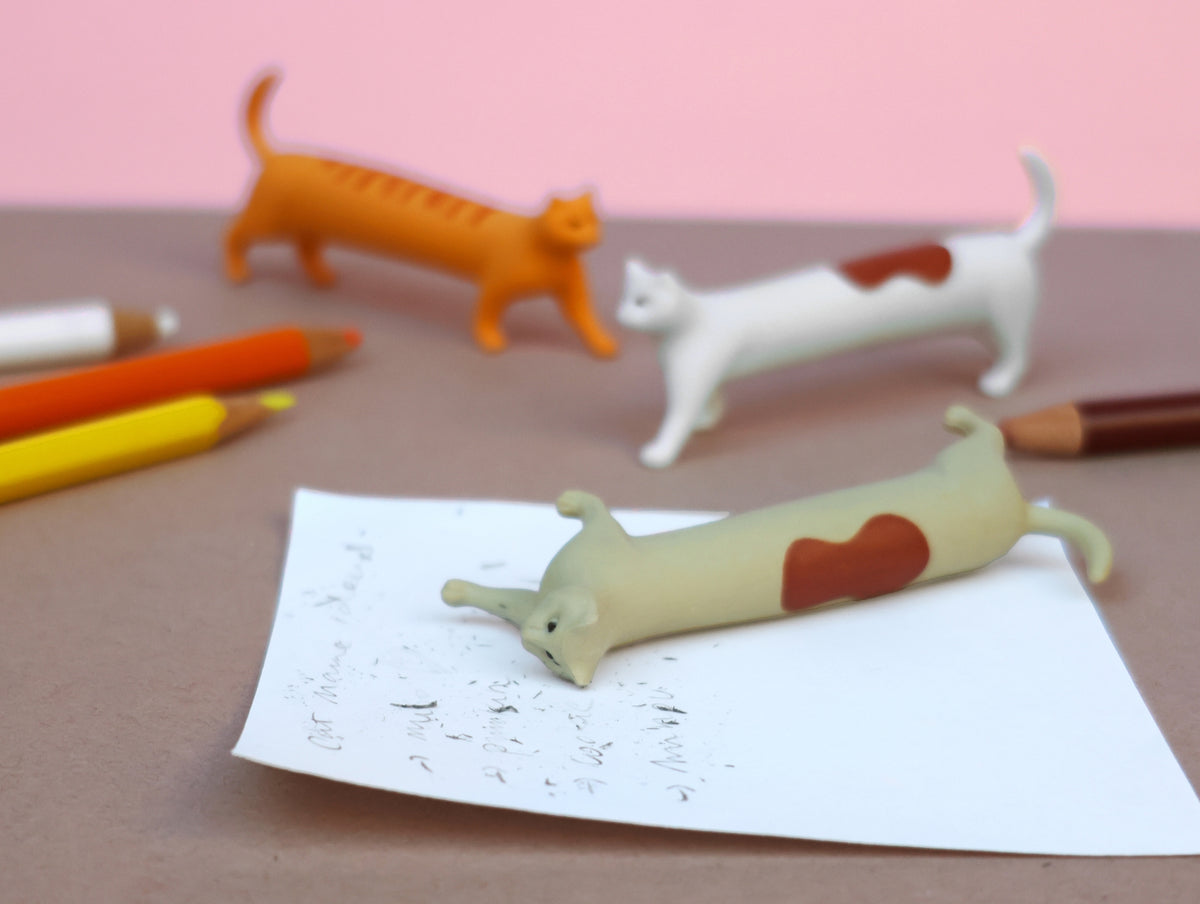 Three cat erasers shown after erasing marks on a piece of paper