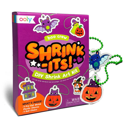 Ooly Boo Crew Shrink-It! DIY Shrink Art Kit box shown with several small Halloween-themed plastic charms attached to green bead chains on a white background.