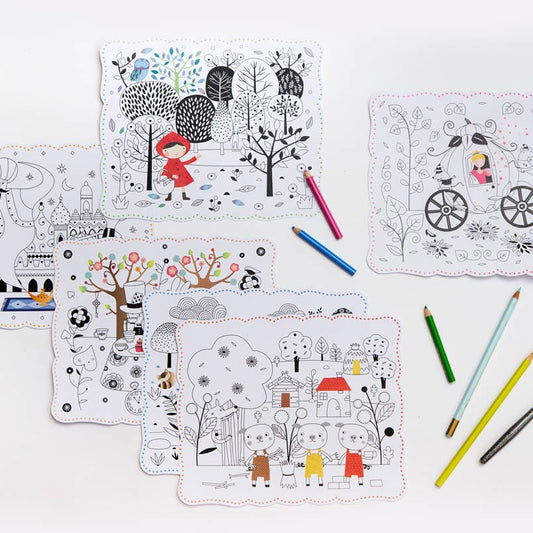 A set of children's coloring cards with whimsical black and white line art, arranged on a white surface alongside colored pencils.