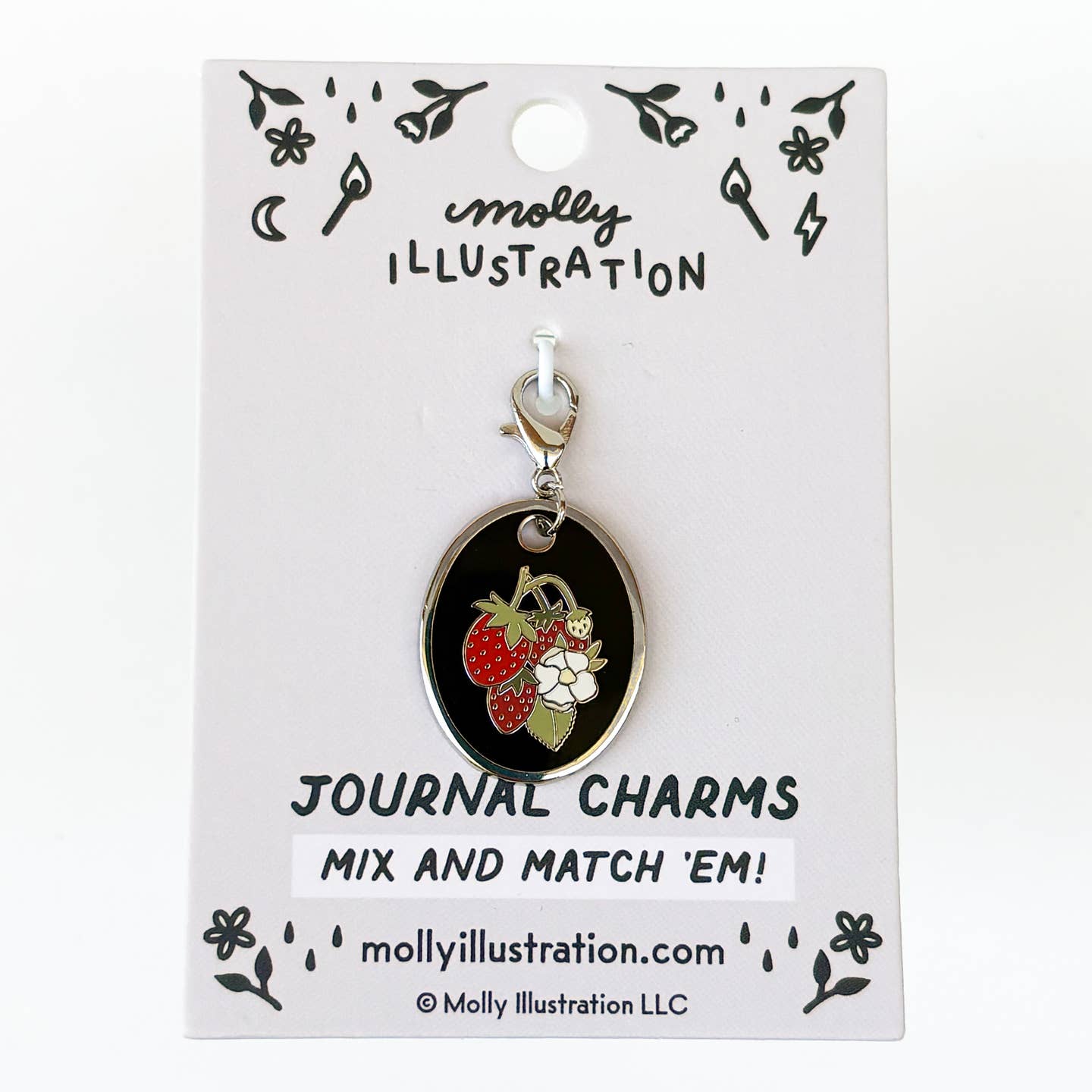 An oval journal charm with a black enamel background and an illustration of red strawberries and white flowers, attached to a silver lobster clasp and displayed on a white backing card branded Molly Illustration.