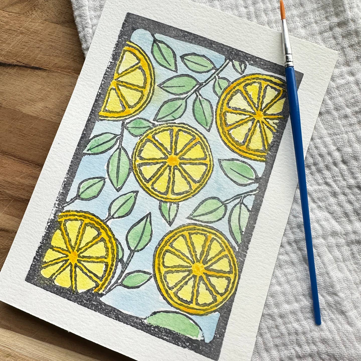 Card with an illustration of many lemon halves with a paintbrush on a wooden background