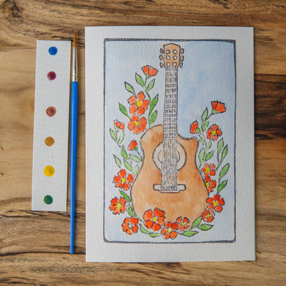 watercolor dot card, paintbrush,  and completed watercolor of a warm brown guitar and orange flowers