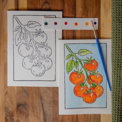 Card with an illustration of tomatoes on the vine with watercolors and a paintbrush on a wooden surface