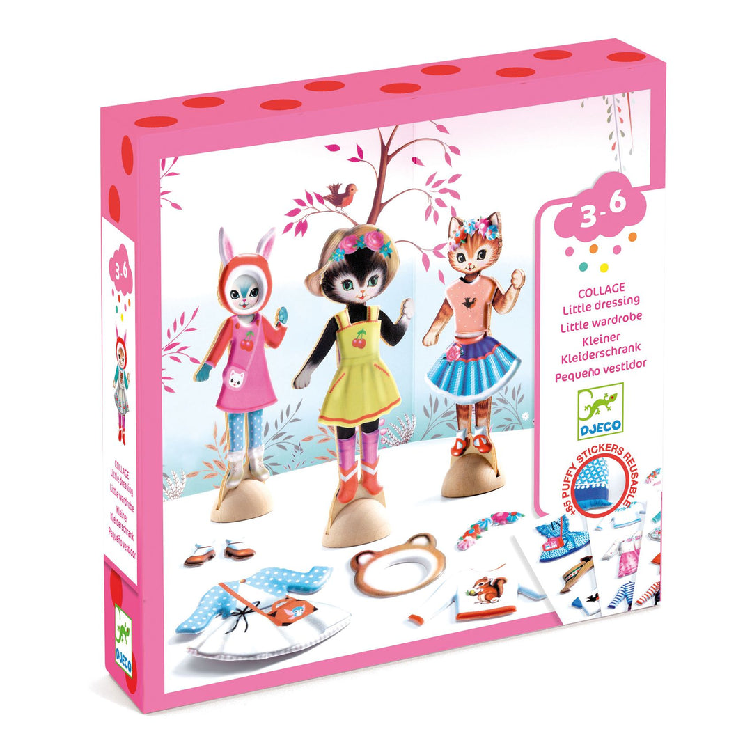 Box with white and pink packaging featuring 3 wooden cat figurines dressed in colorful, fashionable outfits with changes of clothing at their feet