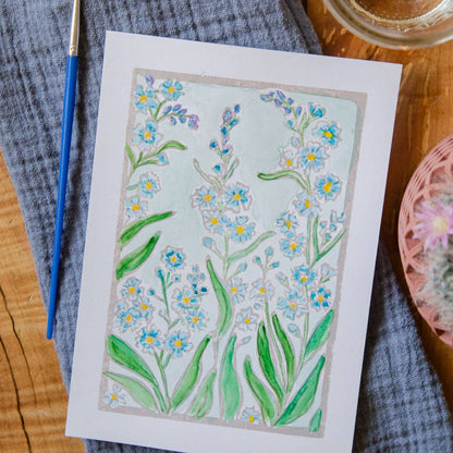 Artistic illustration of flowers on a piece of paper with a paintbrush and glass container in the background.