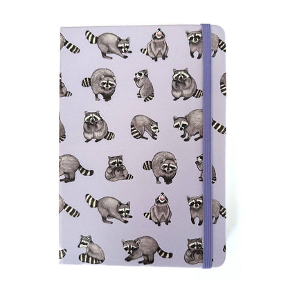 Lavender notebook with a raccoon pattern and a cornflower blue elastic strap closure on a white background