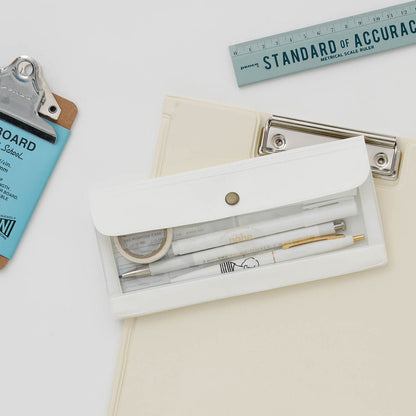 Nahe's General Purpose Wide Organizer in white with a clear window showing three pens and washi tape rolls, laying on a cream colored clipboard with a grey ruler on white background