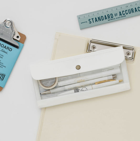 Nahe's General Purpose Wide Organizer in white with a clear window showing three pens and washi tape rolls, laying on a cream colored clipboard with a grey ruler on white background