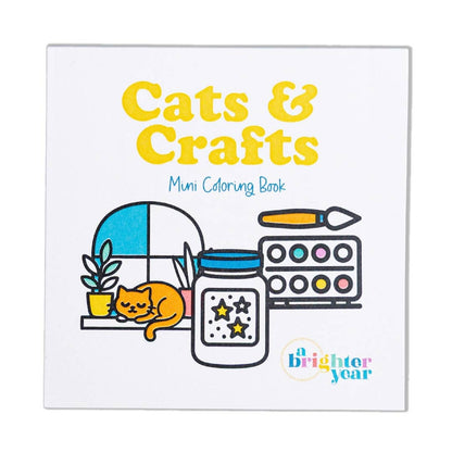 A closeup of the cover of the Crafts & Cats coloring book showing partially colored in images of a cat in a window between two plants, a jar of stars, and a palette of paints