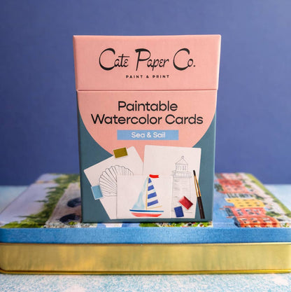 A boxed set of Cate Paper Co. paintable watercolor cards titled 'Sea & Sail,' shown standing upright on a blue and gold tray against a blue background.