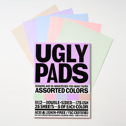 Packaging of "serenity" uglypad with single sheets spread around it in butter, lavender, powder blue, pastel pink, and mint
